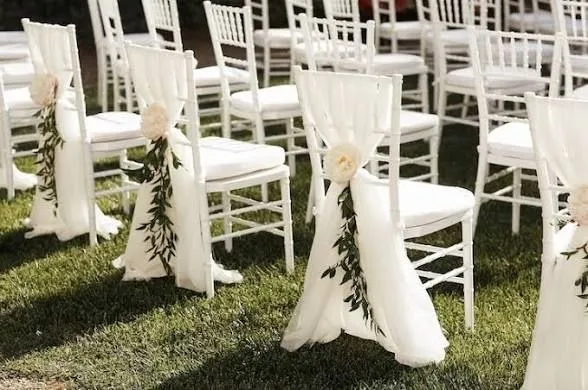 Chaises de cérémonie blanches décorées, alignées en extérieur